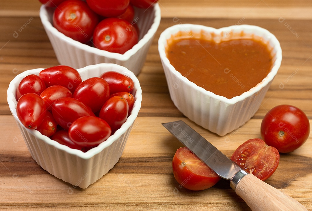 vários tomates pequenos dentro de três tigelas em uma mesa de madeira