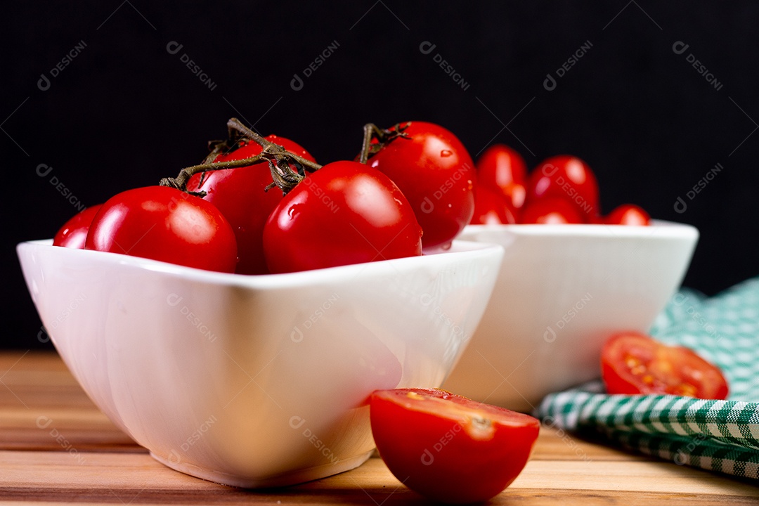 Dois tipos de tomate dentro de uma tigela branca em uma mesa de madeira