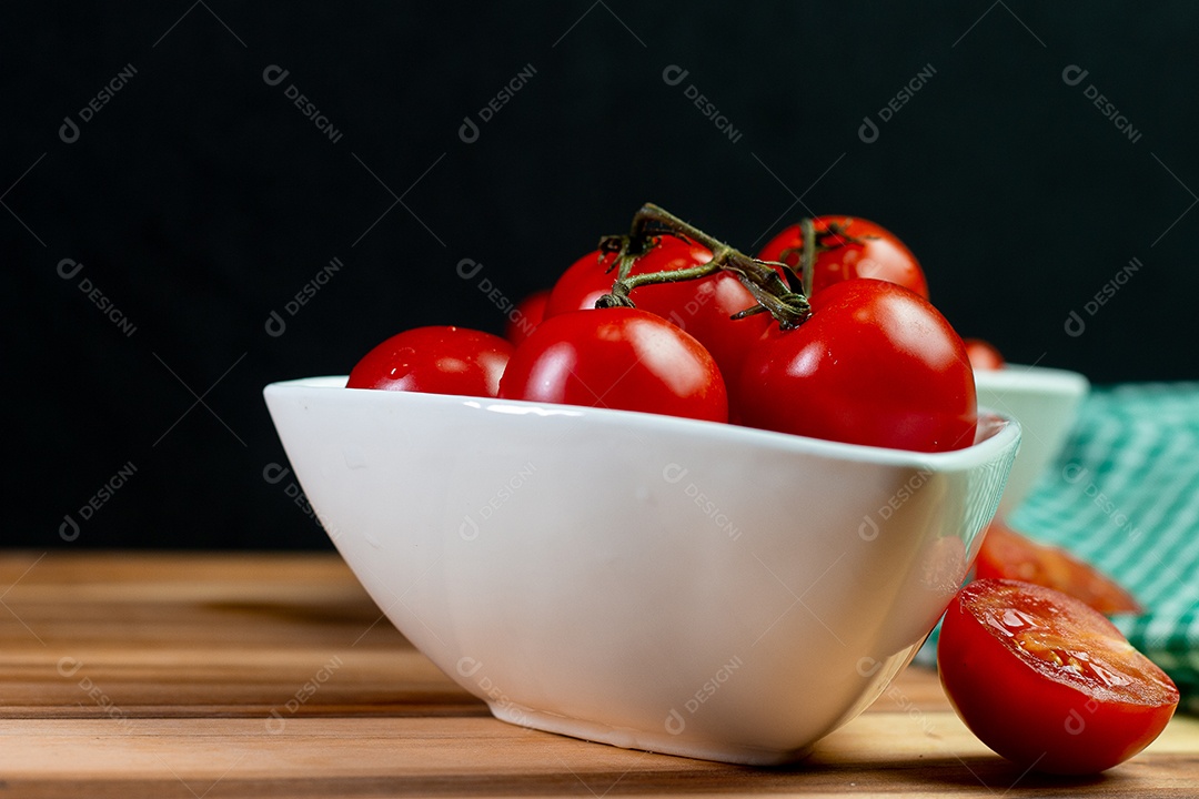 Dois tipos de tomate dentro de uma tigela branca em uma mesa de madeira