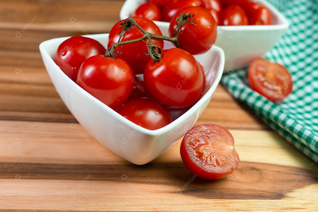 Dois tipos de tomate dentro de uma tigela branca em uma mesa de madeira