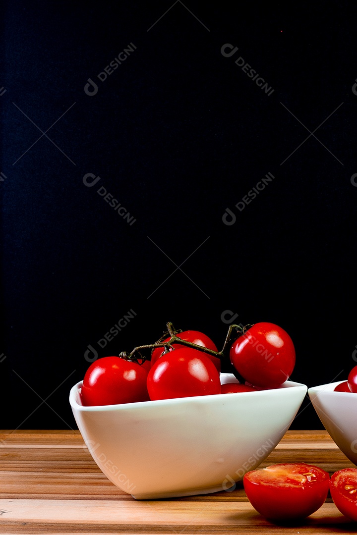 Dois tipos de tomate dentro de uma tigela branca em uma mesa de madeira