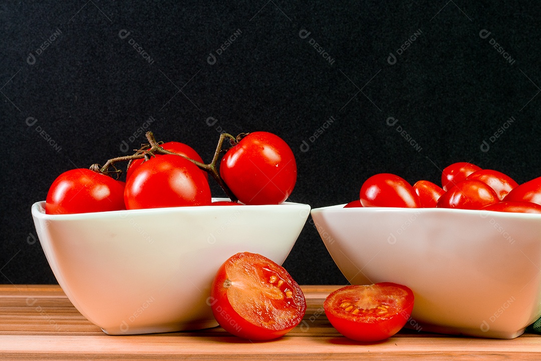 Dois tipos de tomate dentro de uma tigela branca em uma mesa de madeira