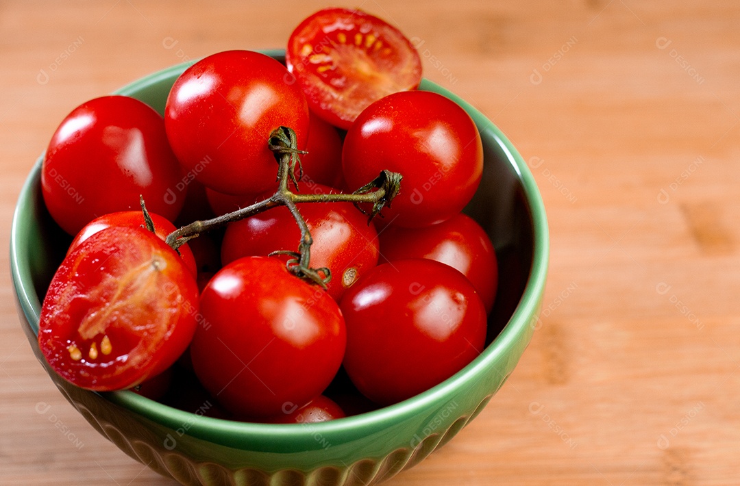 Tomates dentro de uma tigela verde sobre uma mesa de madeira