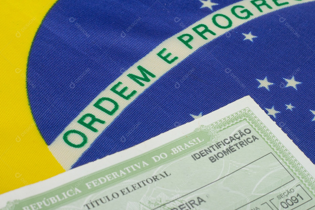 mão segurando o documento eleitoral brasileiro perto da bandeira brasileira