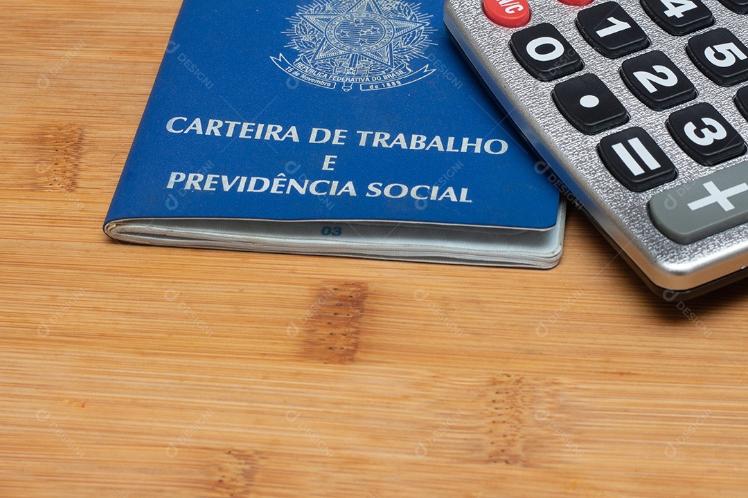 Calculadora encima de carteira de trabalho sobre uma mesa de madeira