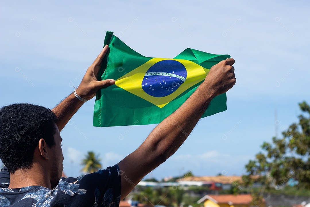homem segurando uma bandeira brasileira na frente da comunidade