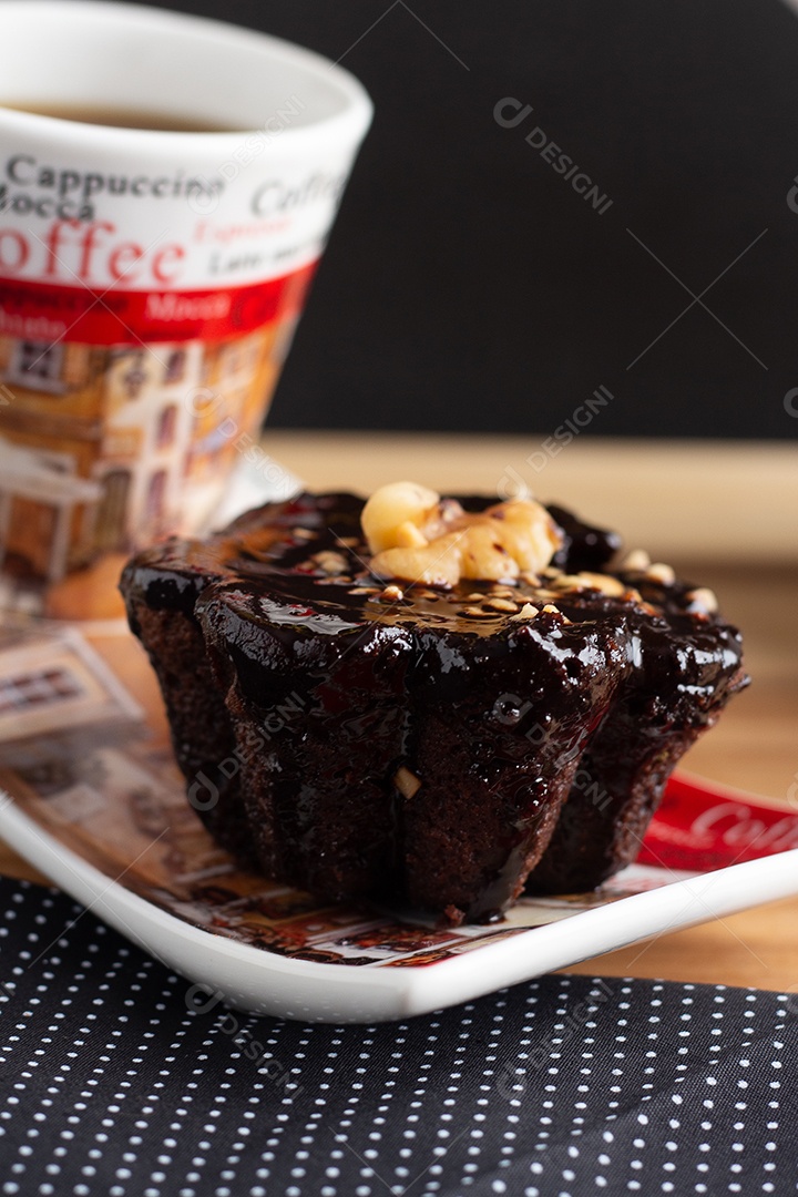 Xícara de café e um bombom de chocolate debaixo da mesa de madeira