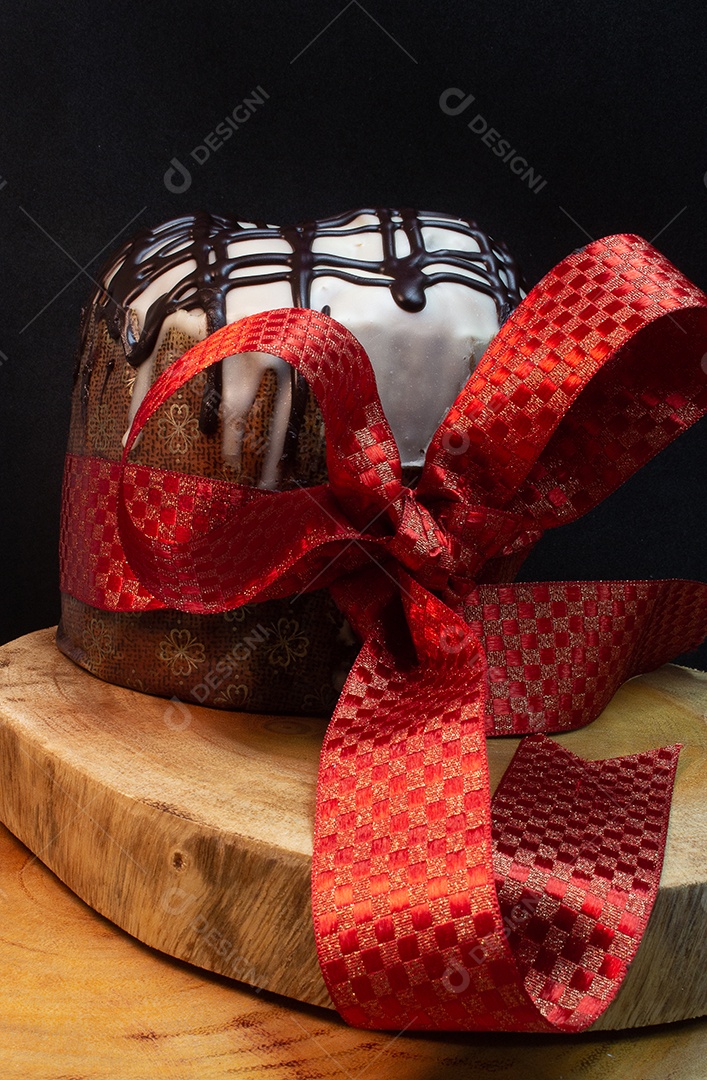 Panetone sobre uma mesa de madeira com gravata vermelha com fundo preto