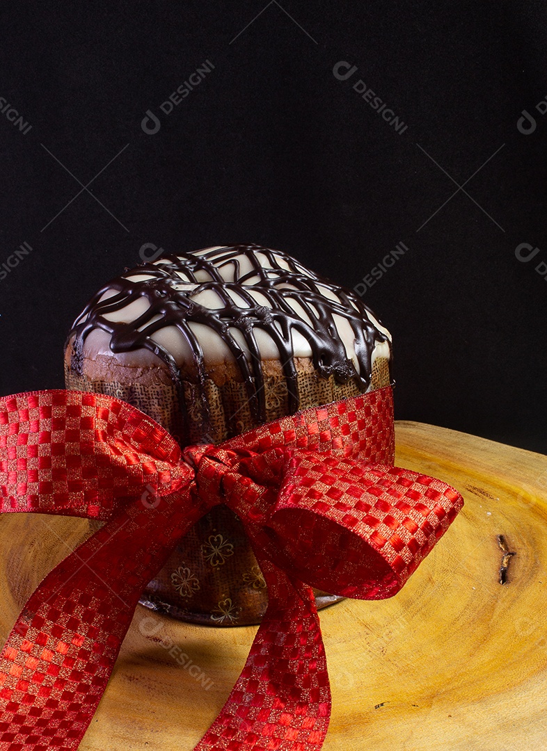 panettone on a wooden table with a red tie on a black background