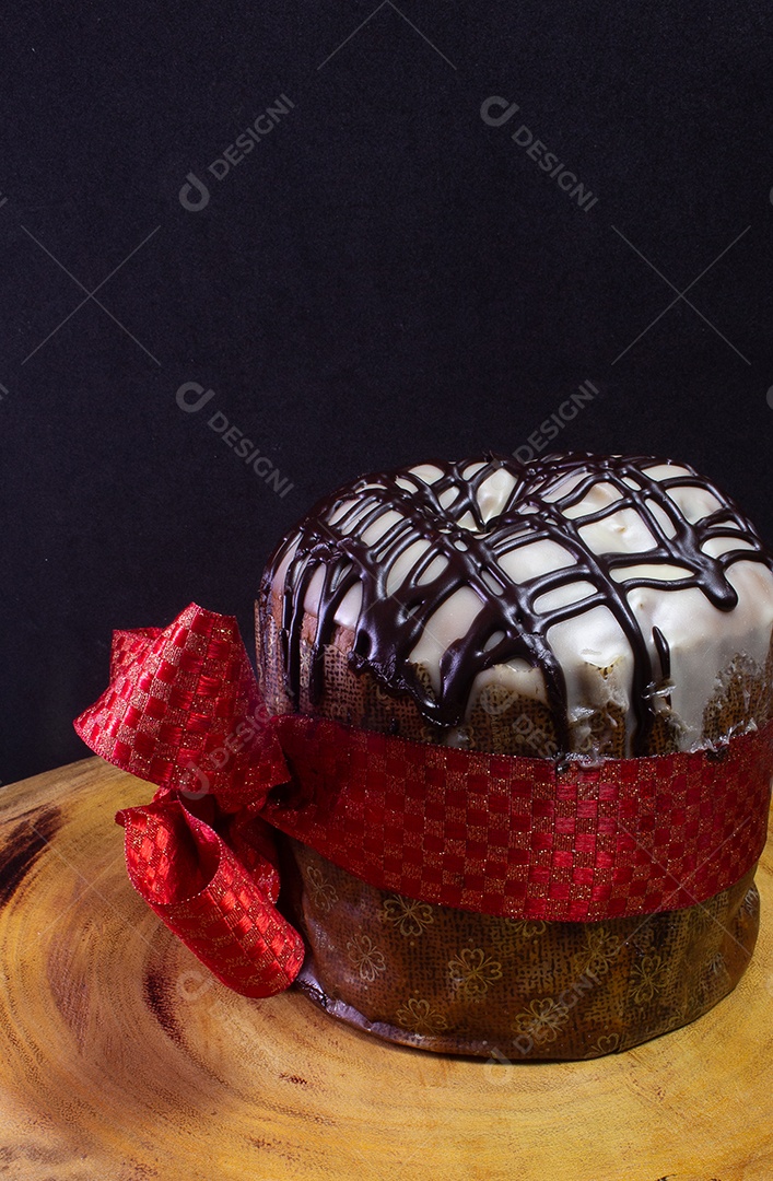 panetone sobre uma mesa de madeira com gravata vermelha com fundo preto