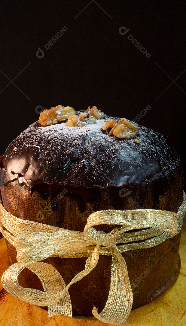 Panetone em uma mesa de madeira com fundo preto cercado