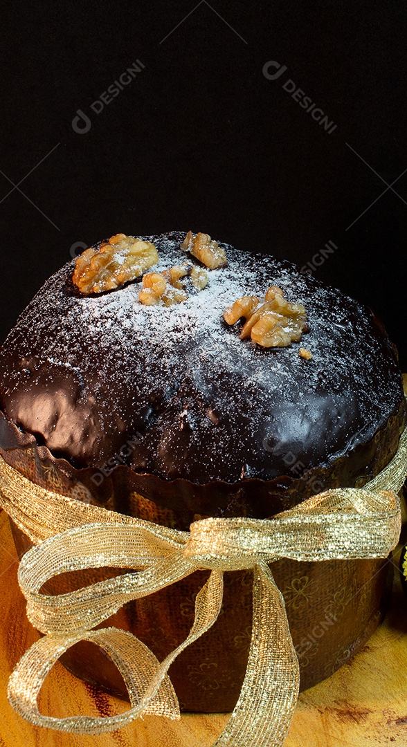Panetone em uma mesa de madeira com fundo preto cercado