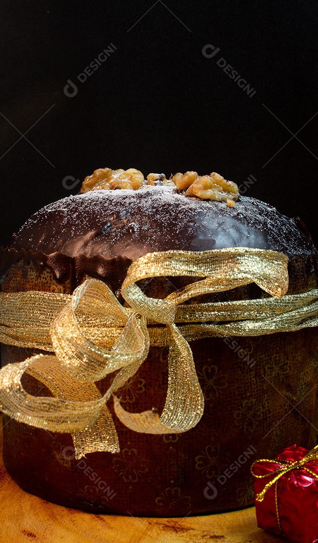 Panetone em uma mesa de madeira com fundo preto cercado