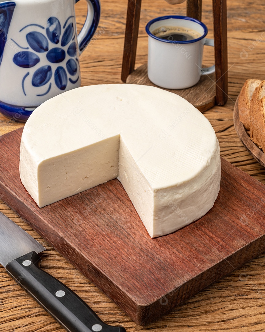 Queijo fresco artesanal de Canastra com café e pão sobre tábua de madeira.