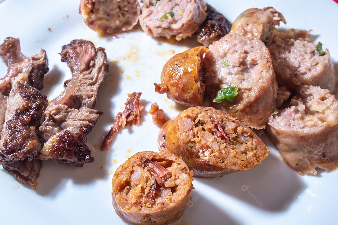 Salsicha assada e fatiada em um prato branco com pequenos pedaços