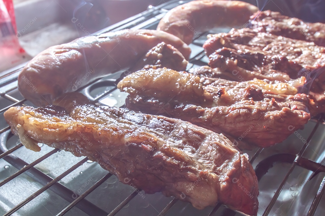 Churrasco em um churrasco elétrico, carnes e salsichas sendo assadas