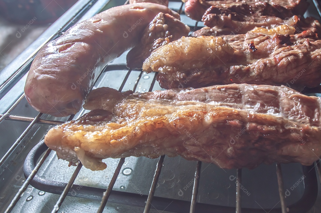 Churrasco em um churrasco elétrico, carnes e salsichas sendo assadas