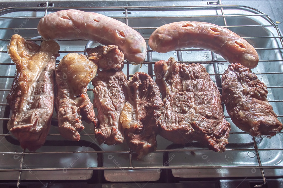 Churrasco em um churrasco elétrico, carnes e salsichas sendo assadas