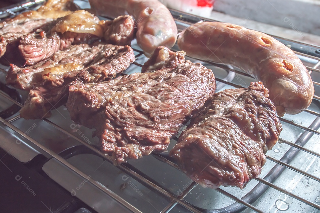 Churrasco em um churrasco elétrico, carnes e salsichas sendo assadas