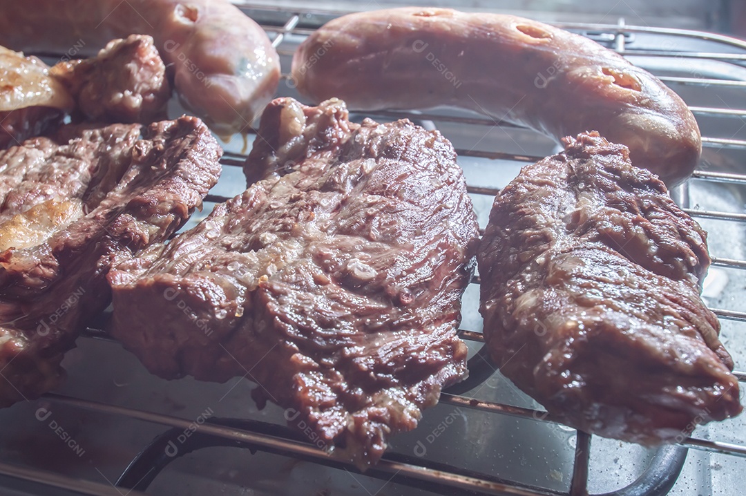 Churrasco em um churrasco elétrico, carnes e salsichas sendo assadas