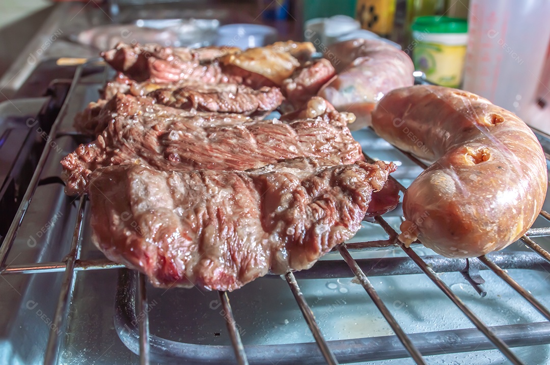 Churrasco em um churrasco elétrico, carnes e salsichas sendo assadas