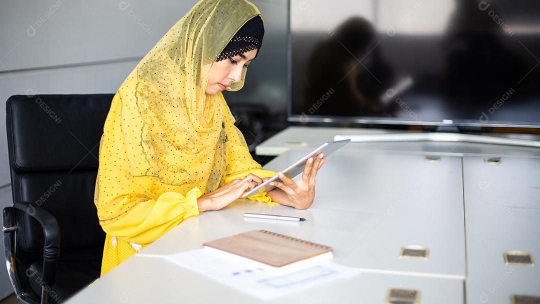 Uma empresária está usando um tablet para trabalhar e está estressada em sua mesa.