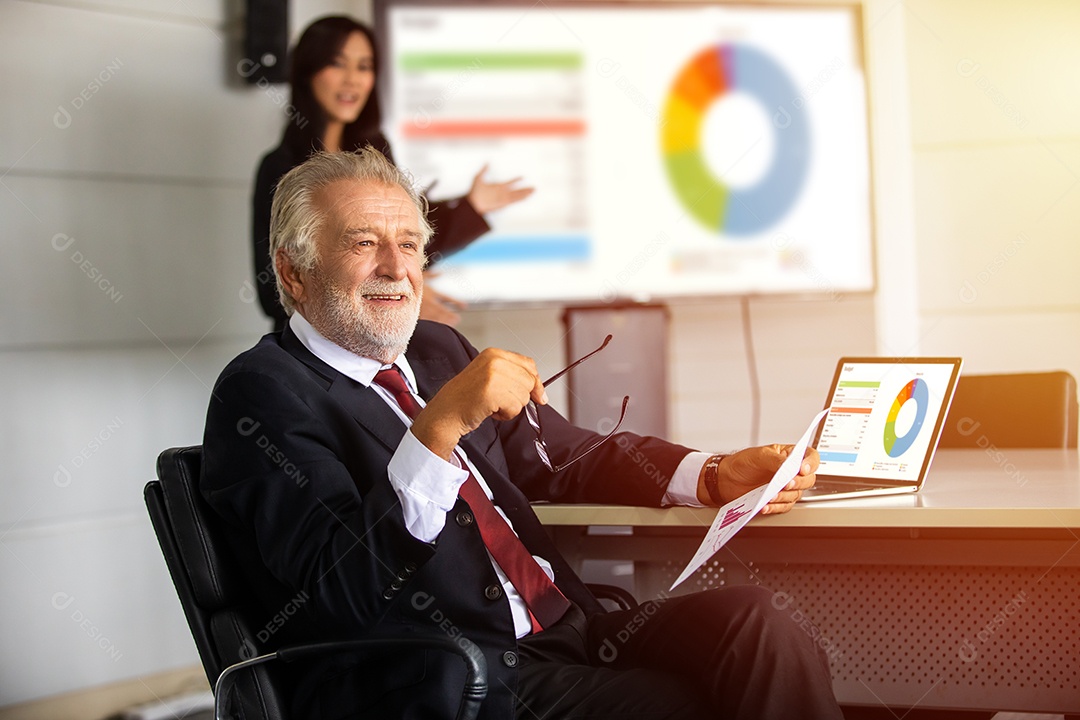 Empresário idoso sentado em uma reunião e verificando documentos com notebooks em uma mesa em uma sala de reuniões