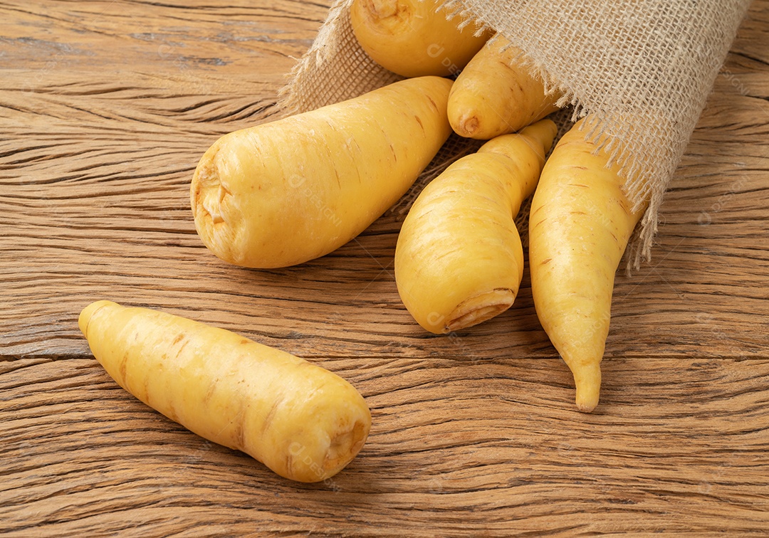 Mandioquinha crua ou arracacha sobre mesa de madeira.