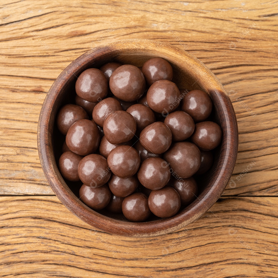 Bolas de chocolate maltadas em uma tigela sobre a mesa de madeira.