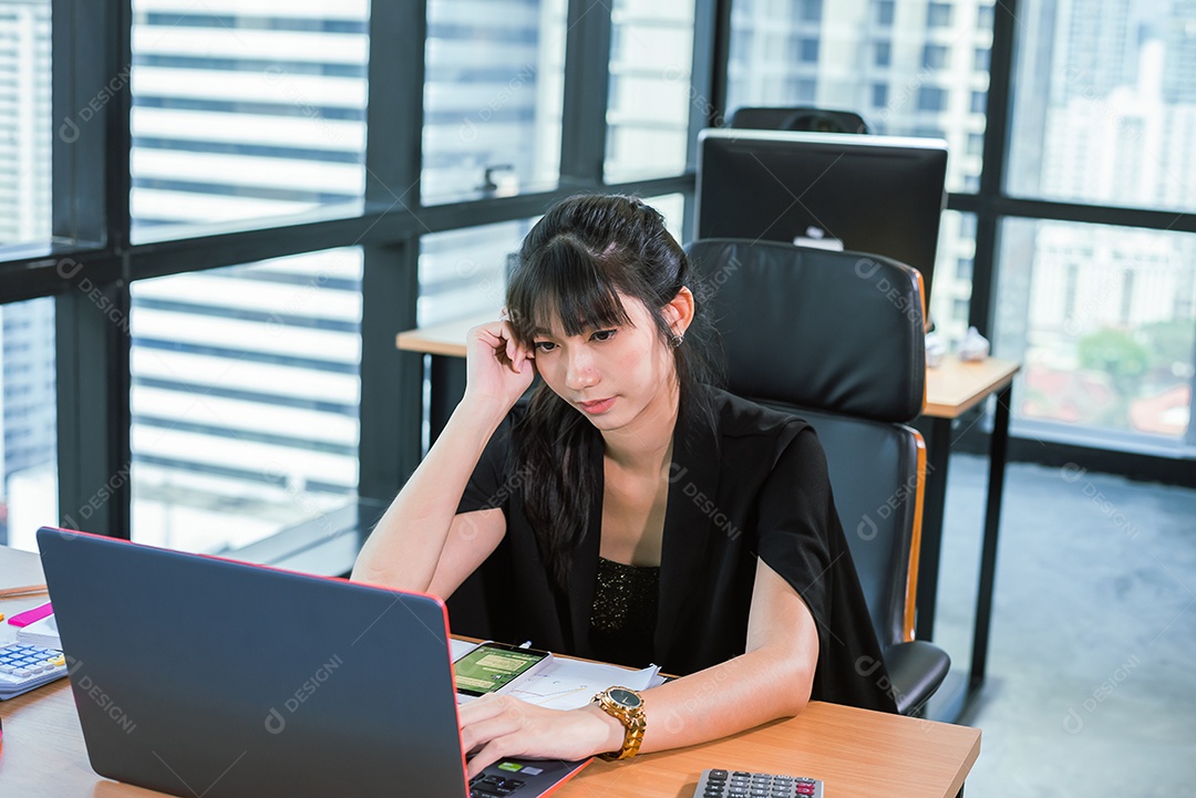 Mulher asiática de negócios sente-se no escritório moderno e sério do trabalho