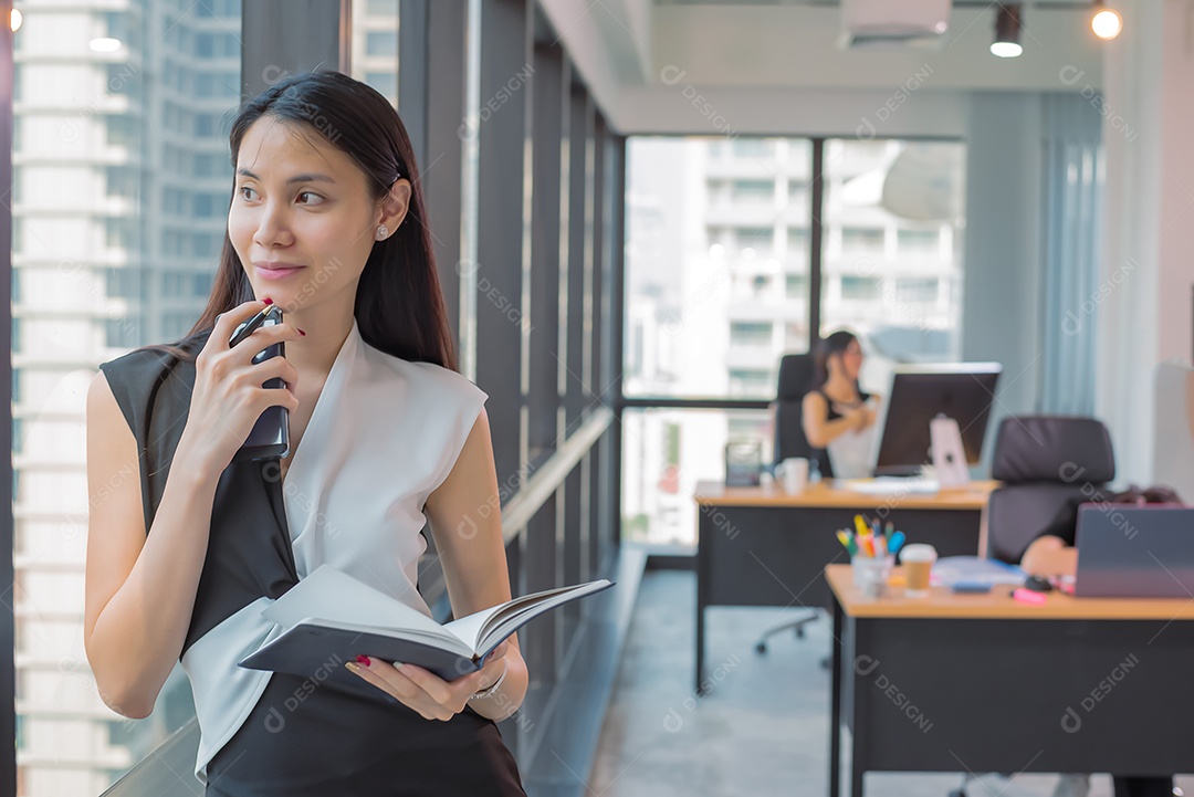 Mulher asiática de negócios fica olhando para fora no escritório moderno