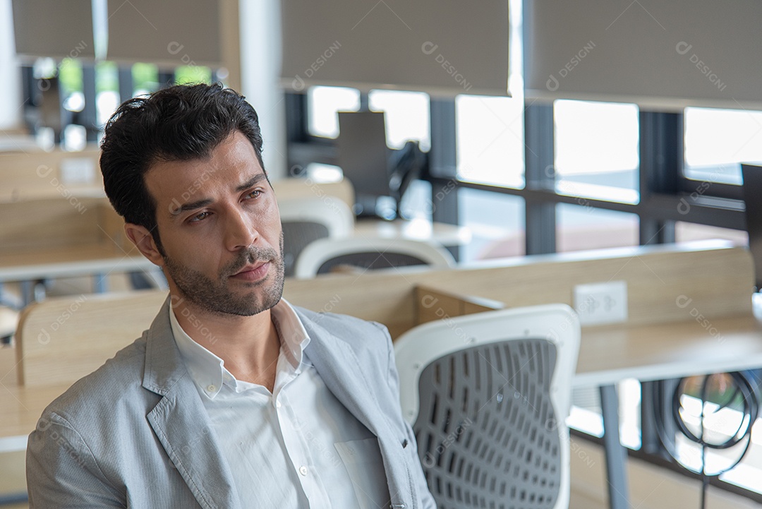 O homem de negócios senta-se no escritório sério e preocupa-se