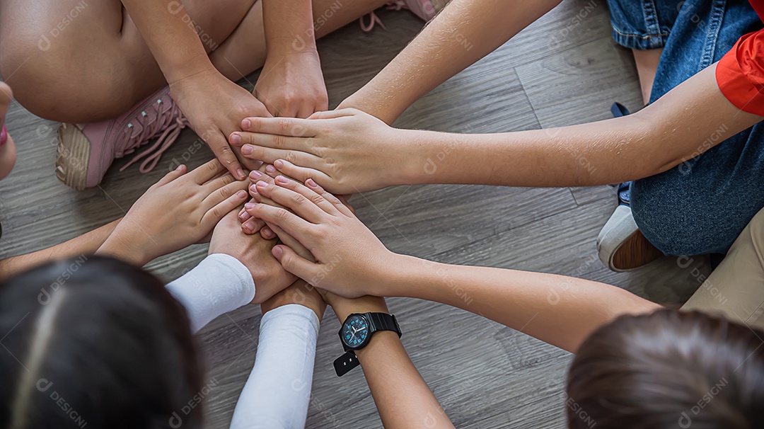 Meninas e meninos internacionais da escola primária dão as mãos para