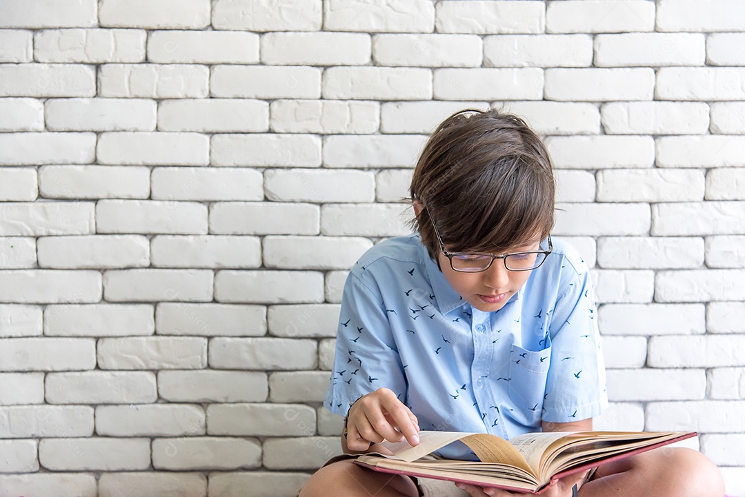 Estudante de escola secundária usando óculos sentado lendo livro
