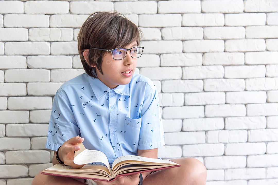Estudante de escola secundária usando óculos sentado lendo livro