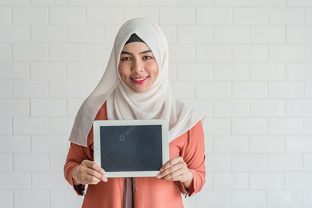 Mulher muçulmana em pé, segure a exibição em branco do tablet para anúncios