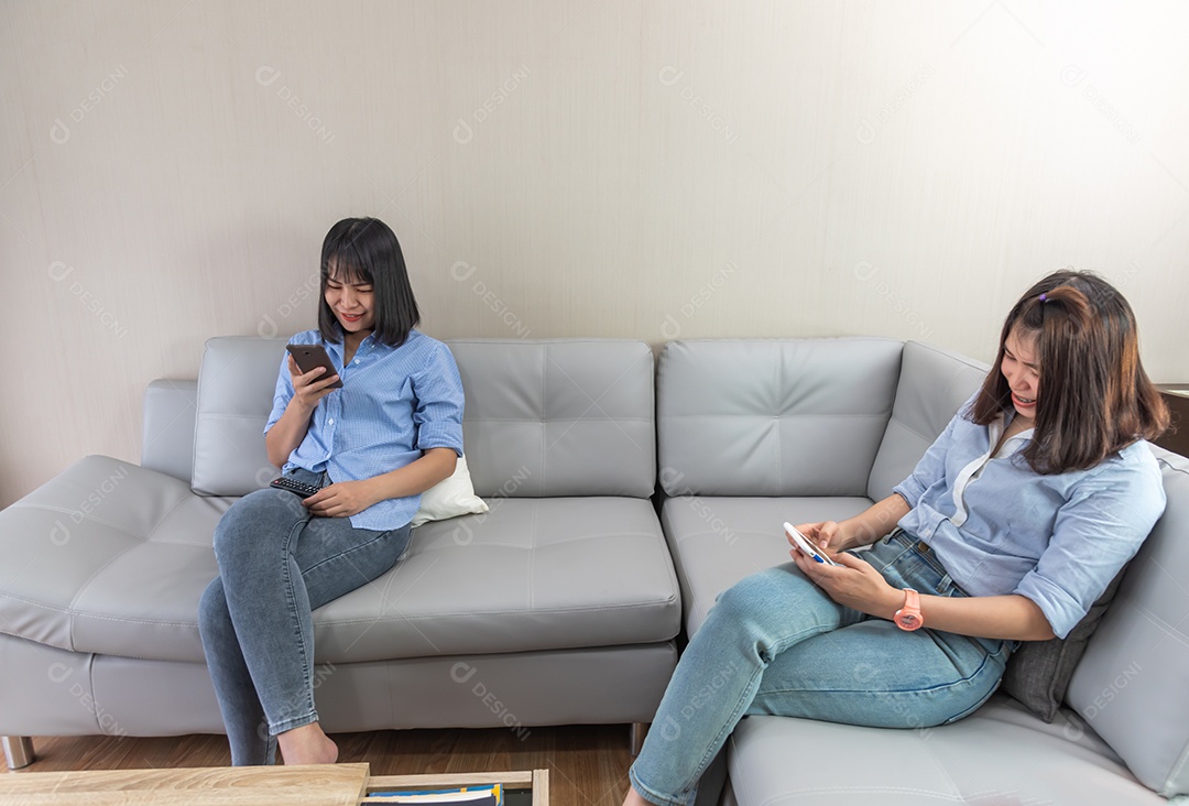 Duas mulheres asiáticas usam o telefone inteligente, verificam o e-mail