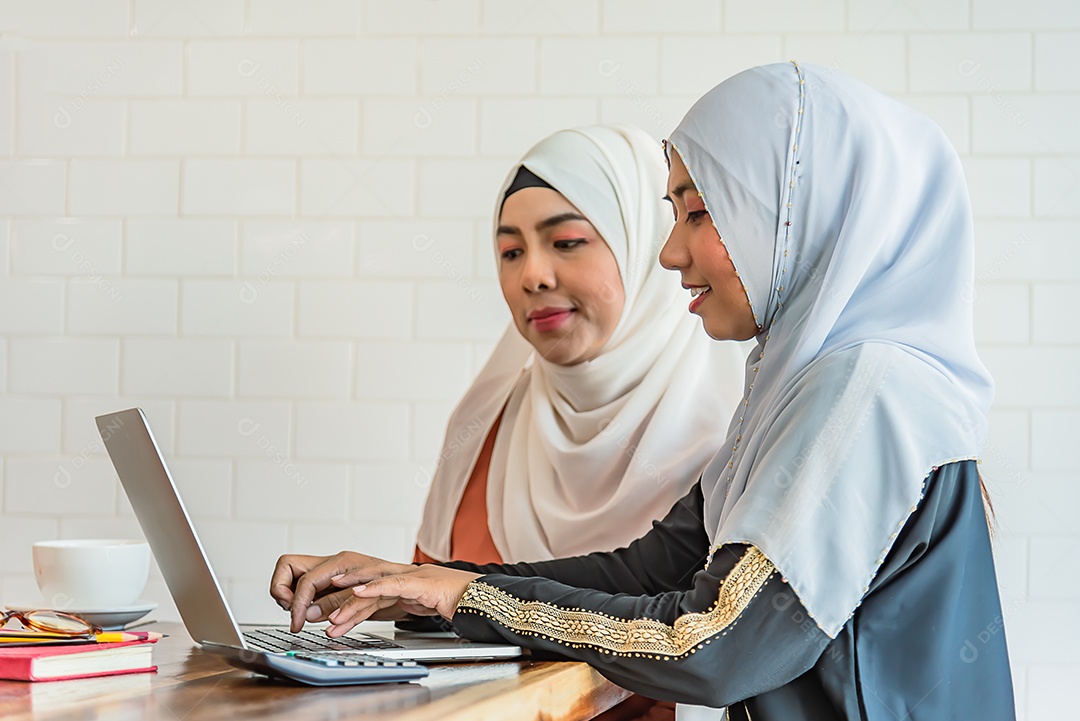 Duas mulheres muçulmanas usam notebook em casa, procuram internet