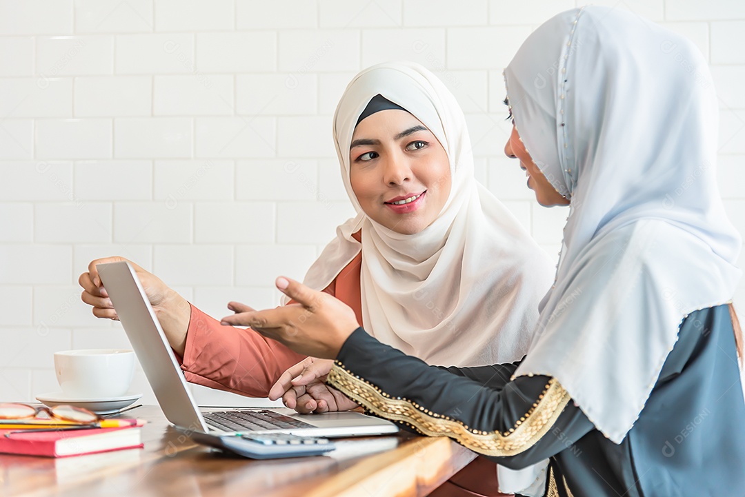 Duas mulheres muçulmanas usam notebook em casa, procuram internet