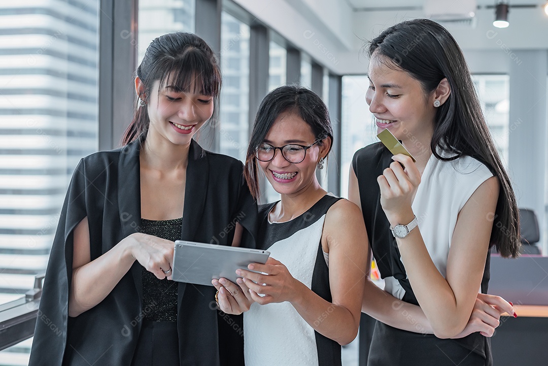 Tablet de aparência de três mulheres de negócios asiáticos em escritório moderno