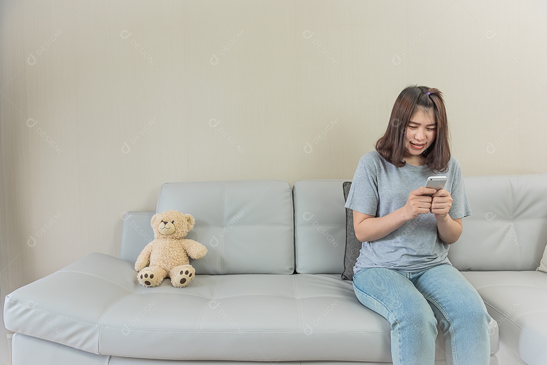 Mulher asiática sente-se no sofá, use o telefone inteligente, verifique o e-mail, menina asiática