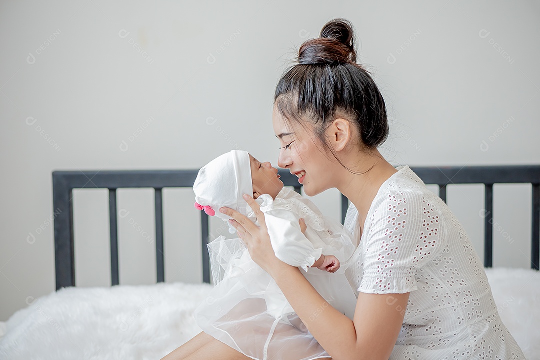 Bebê dorme no colo da mãe, mãe asiática carrega e toca nele
