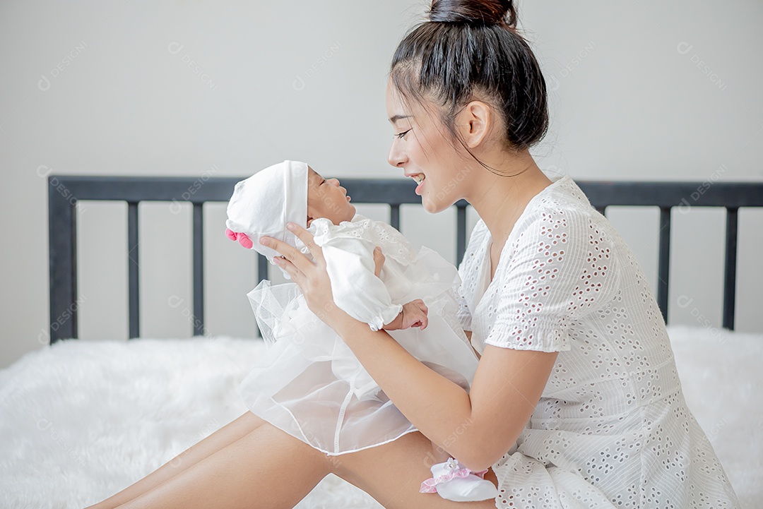 Bebê dorme no colo da mãe, mãe asiática carrega e toca nele