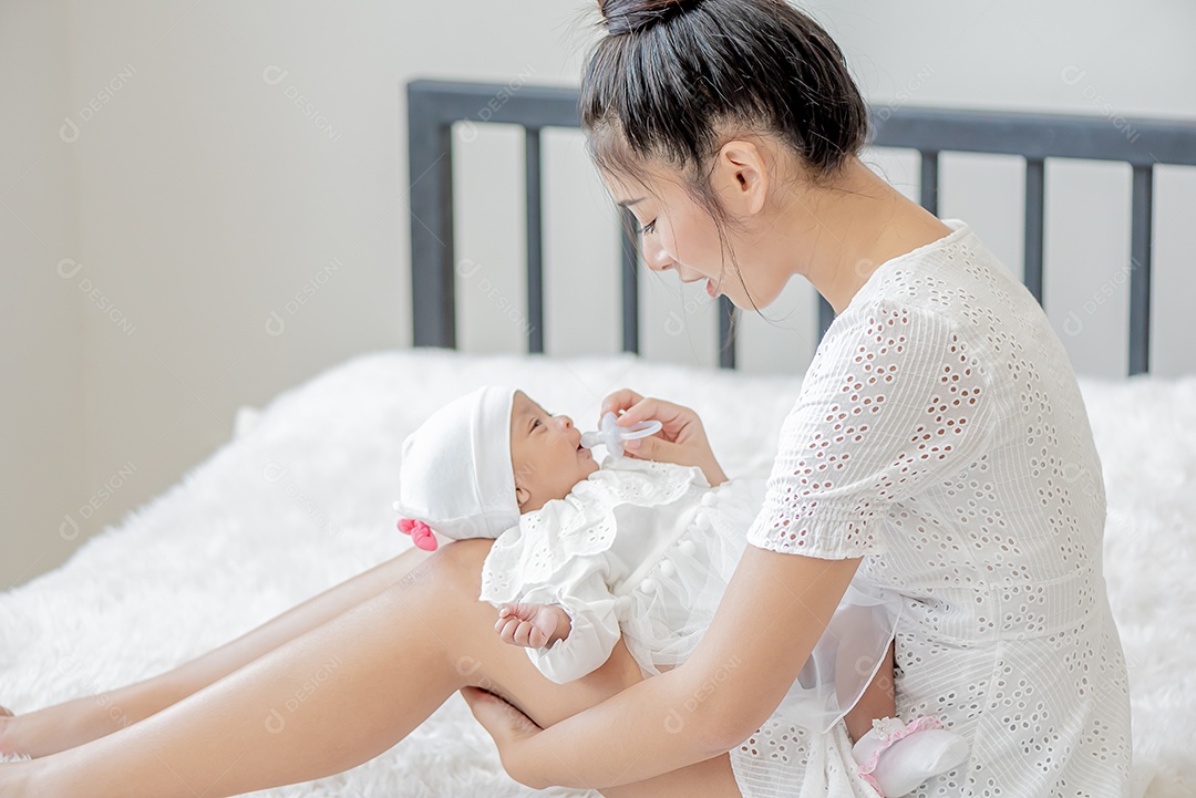 Bebê dorme no colo da mãe, mãe asiática carrega e toca nele