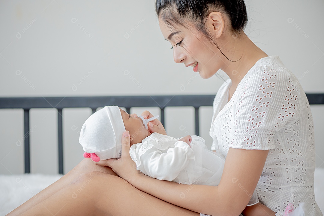 Bebê dorme no colo da mãe, mãe asiática carrega e toca nele