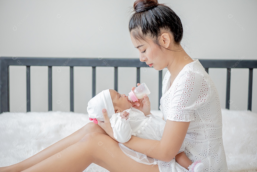 Bebê dorme no colo da mãe, mãe asiática carrega e toca nele