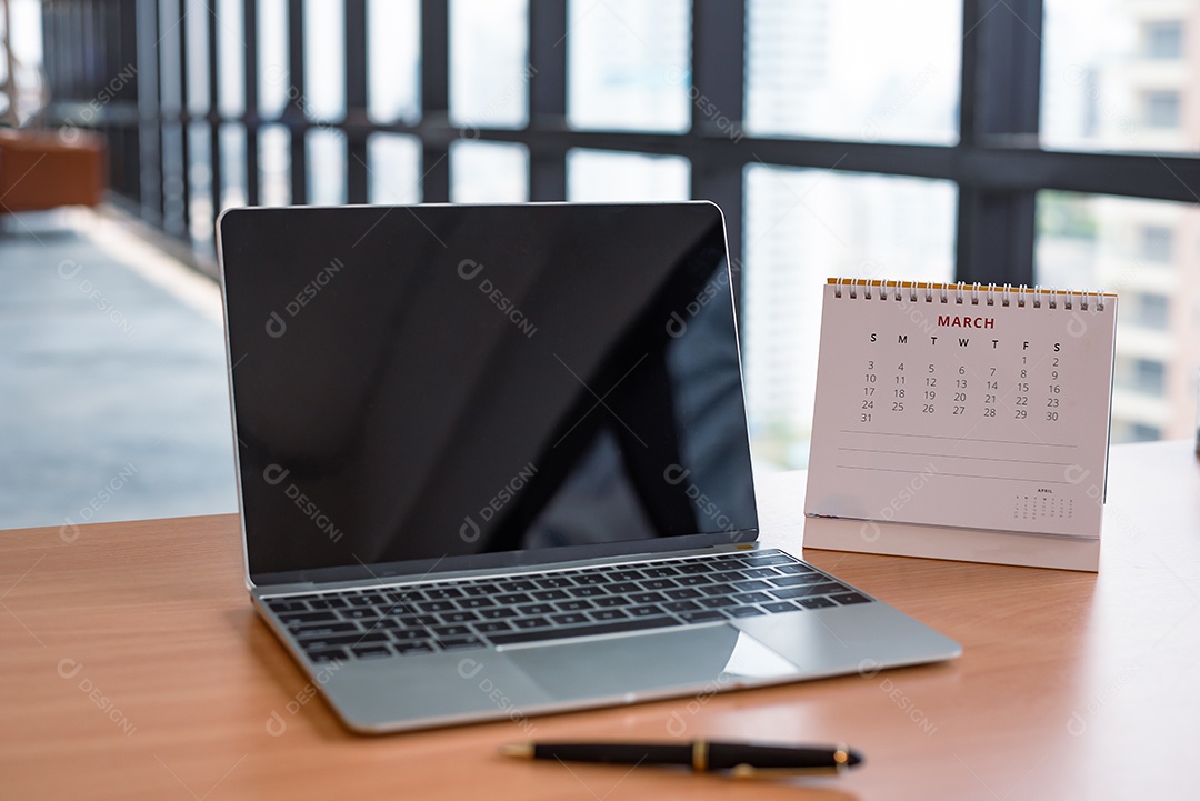 Caderno de computador com tela preta em branco e calendário na mesa