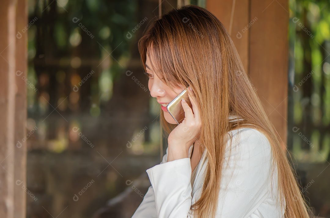 Linda mulher de negócios asiáticos usa telefone inteligente falando com seu amigo, família interior, feliz e sorriso.