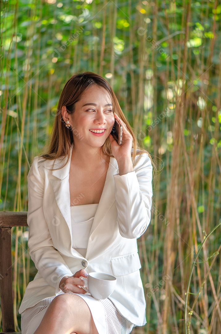 Linda mulher de negócios asiáticos usa telefone inteligente falando com seu amigo, família interior, feliz e sorriso.