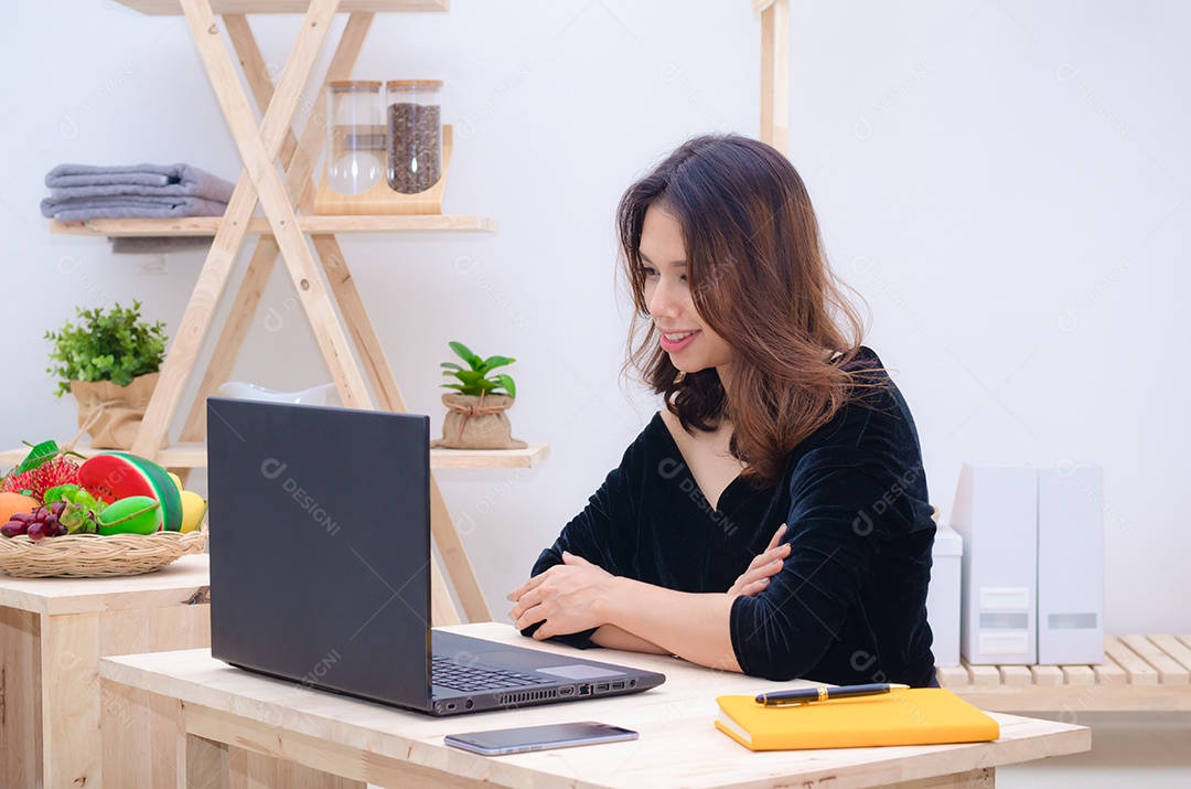 Linda mulher asiática está relaxando usando o notebook do computador na cama.